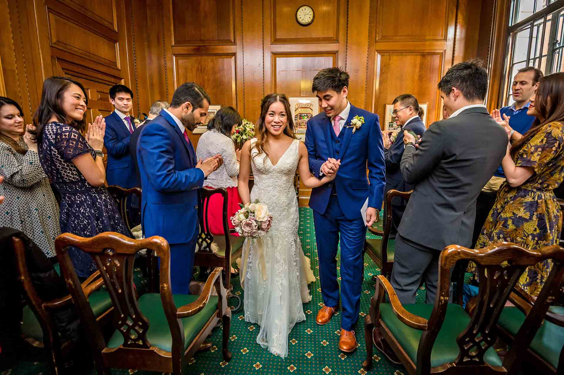 Couple at Camden Town Hall Wedding Walking Back Down Aisle with Guests Watching